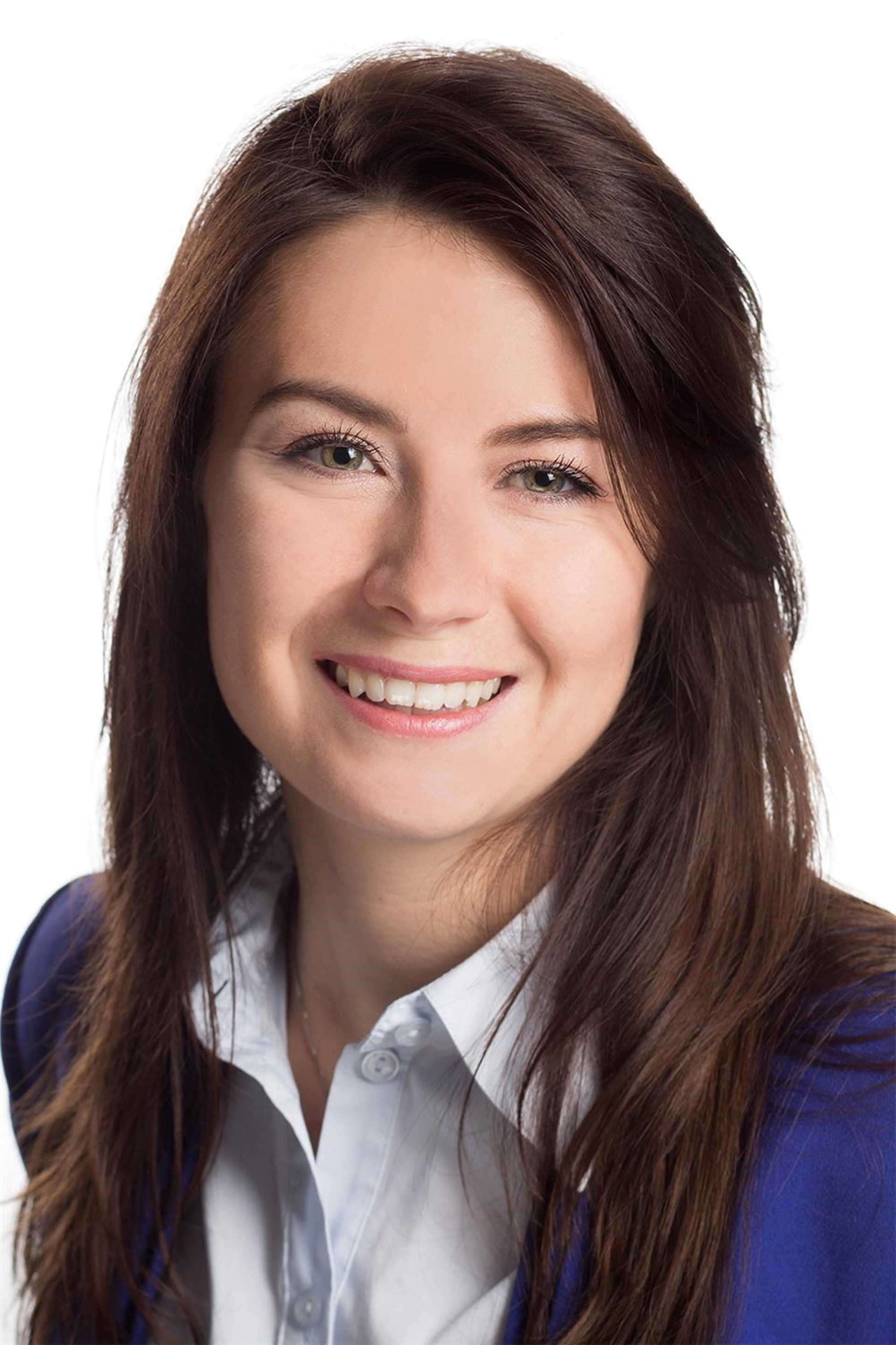 Lächelnde Frau mit langen braunen Haaren, blauem Blazer und weißer Bluse.